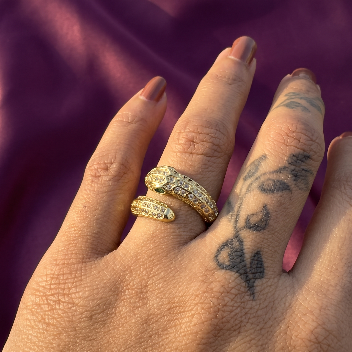 Hand wearing gold crystal snake wrap ring with green eye – sparkling serpent party wear ring, perfect gift for her